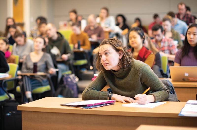 以一个学生为中心的班级. 那个学生正在做笔记，眼睛望着教室前面.